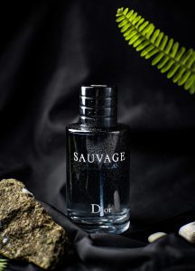 a bottle of cologne sitting next to a rock