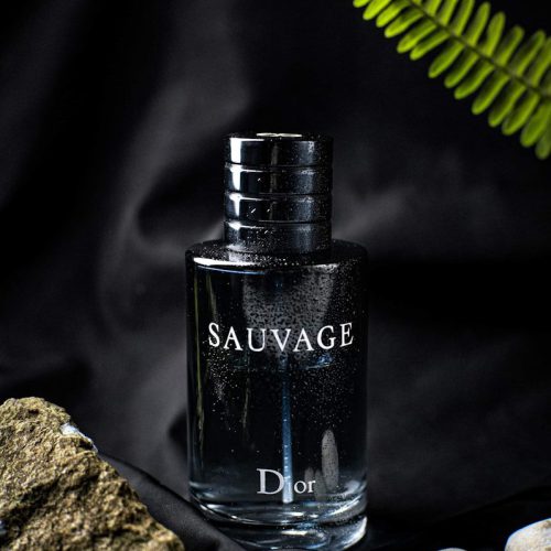 a bottle of cologne sitting next to a rock